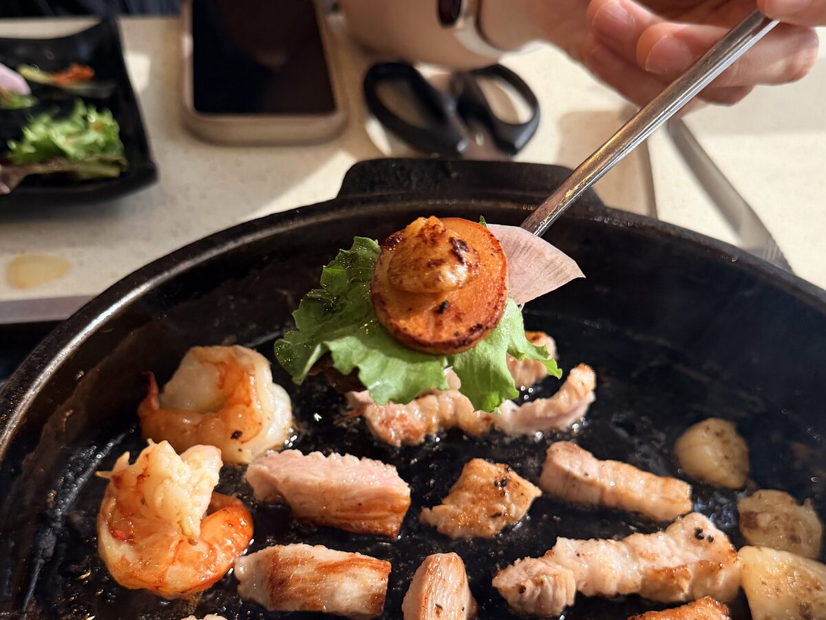 Grilled Hokkaido scallop over lettuce, prawns and pork belly on the pan at KOSOO